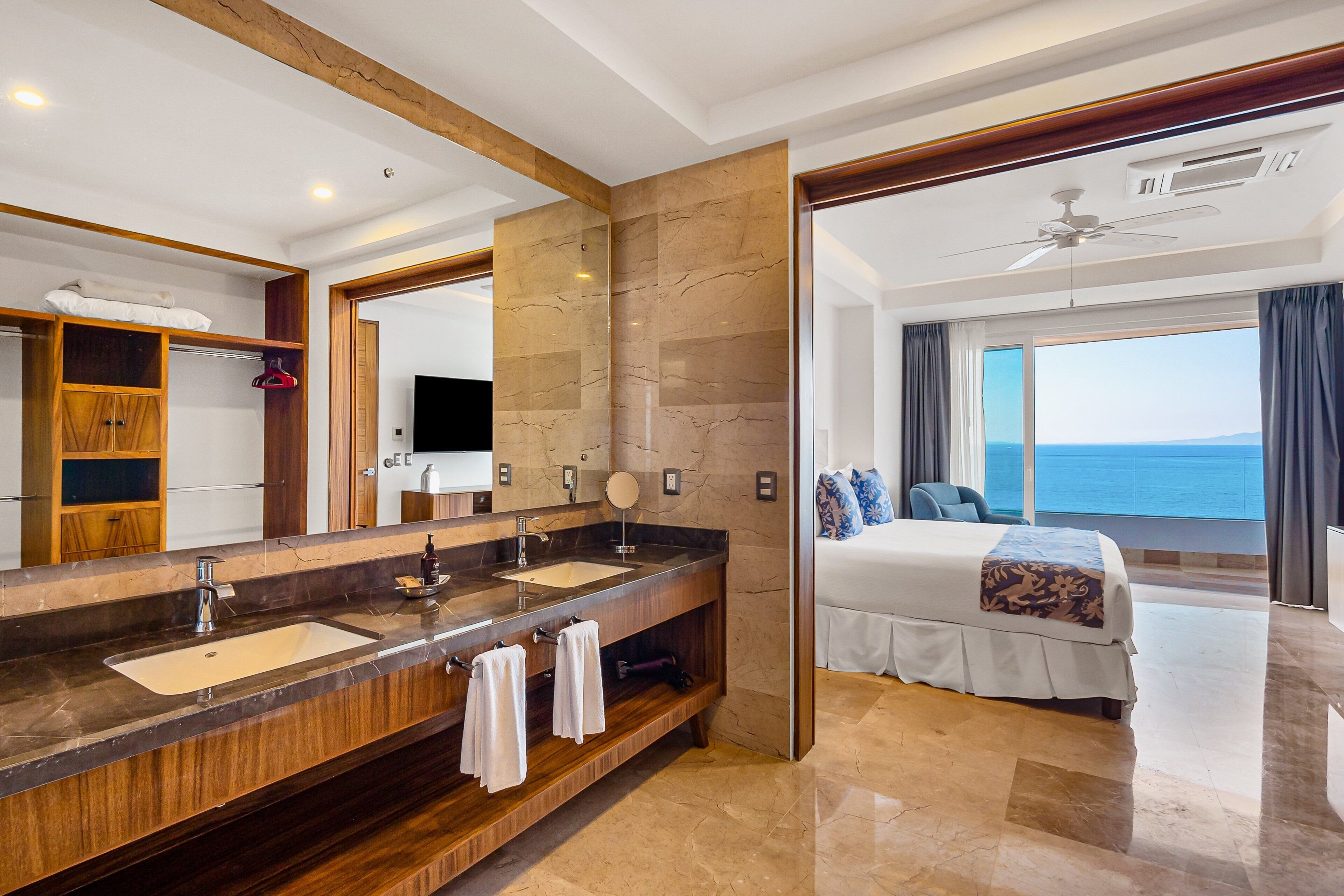 Habitación de hotel con un amplio tocador de baño, una cama con vistas y un ventilador de techo.