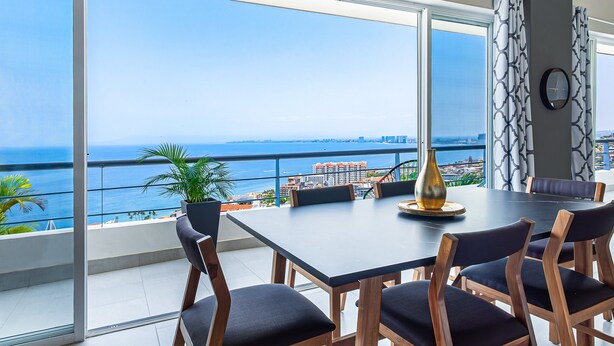 A dining area with a large table, chairs, and a view of the ocean. - Dog-friendly Ocean View Penthouse & Studio With a Full Kitchen & Kitchenette (Puerto Vallarta)