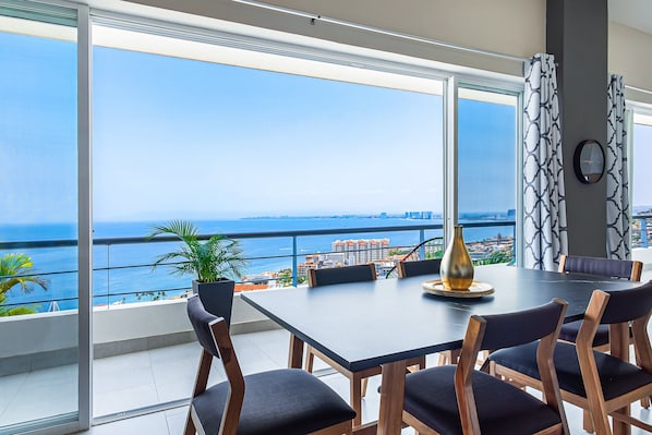 Un espace repas comprenant une grande table, des chaises et une vue sur l’océan.
