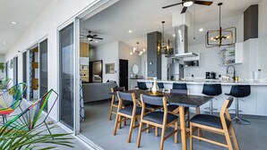 A modern kitchen with a central island, dining area with chairs, and a ceiling fan. - Dog-friendly Ocean View Penthouse & Studio With a Full Kitchen & Kitchenette (Puerto Vallarta)