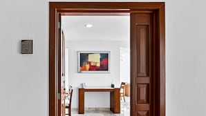 A hallway with a wooden door, a desk, chairs, and a painting on the wall. - Modern Coastal Villa With Ocean Views, Pool, Wifi & Full Kitchen (Puerto Vallarta)
