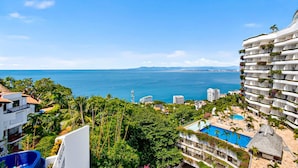 A coastal hotel with multiple balconies, a swimming pool, and lush greenery. - Modern Coastal Villa With Ocean Views, Pool, Wifi & Full Kitchen (Puerto Vallarta)