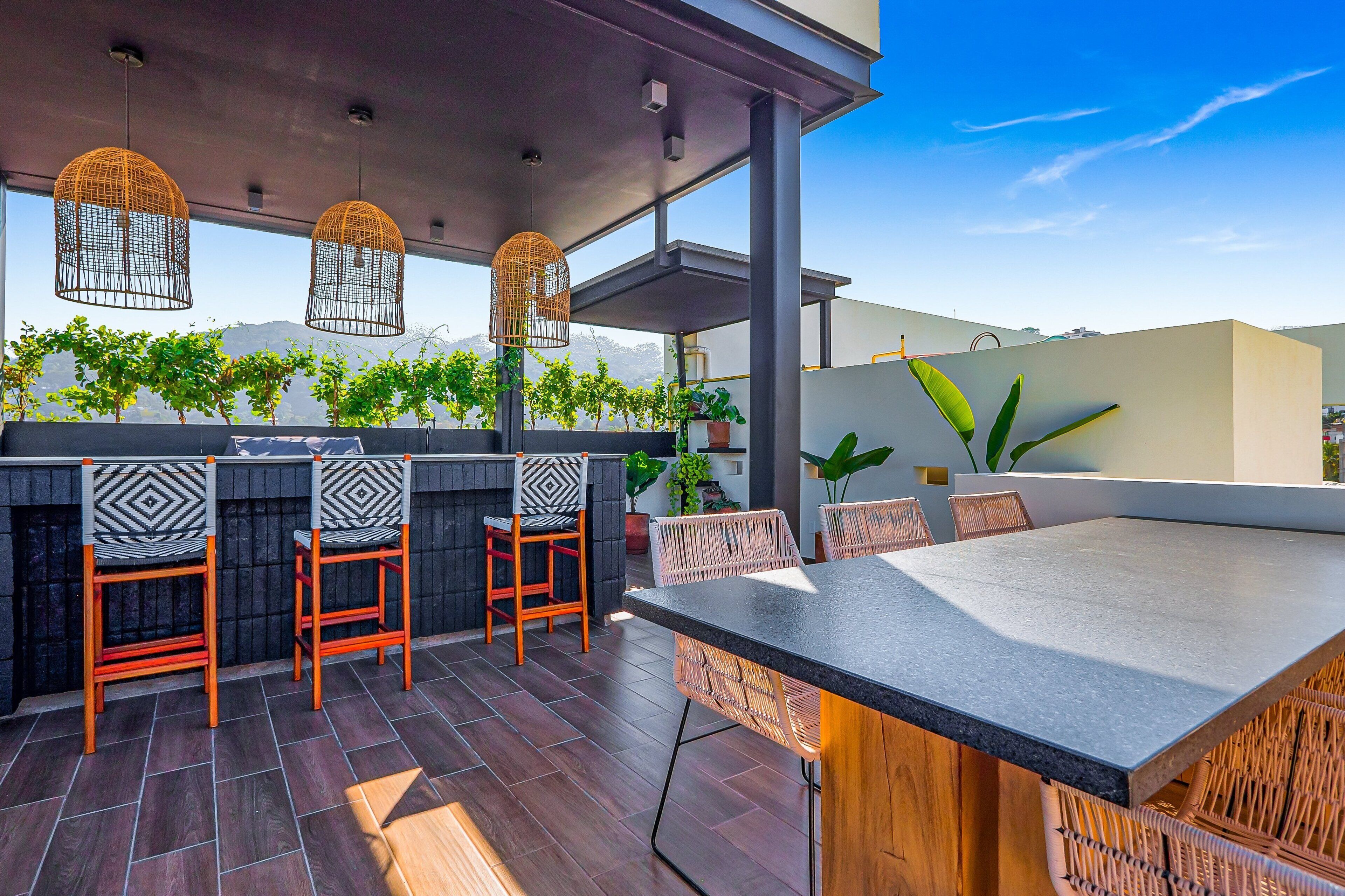 Une terrasse extérieure avec un coin bar, des chaises et des guirlandes lumineuses.