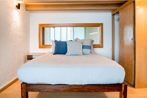 Un dormitorio con una cama grande, cabecera de madera, mesita de noche y un armario.