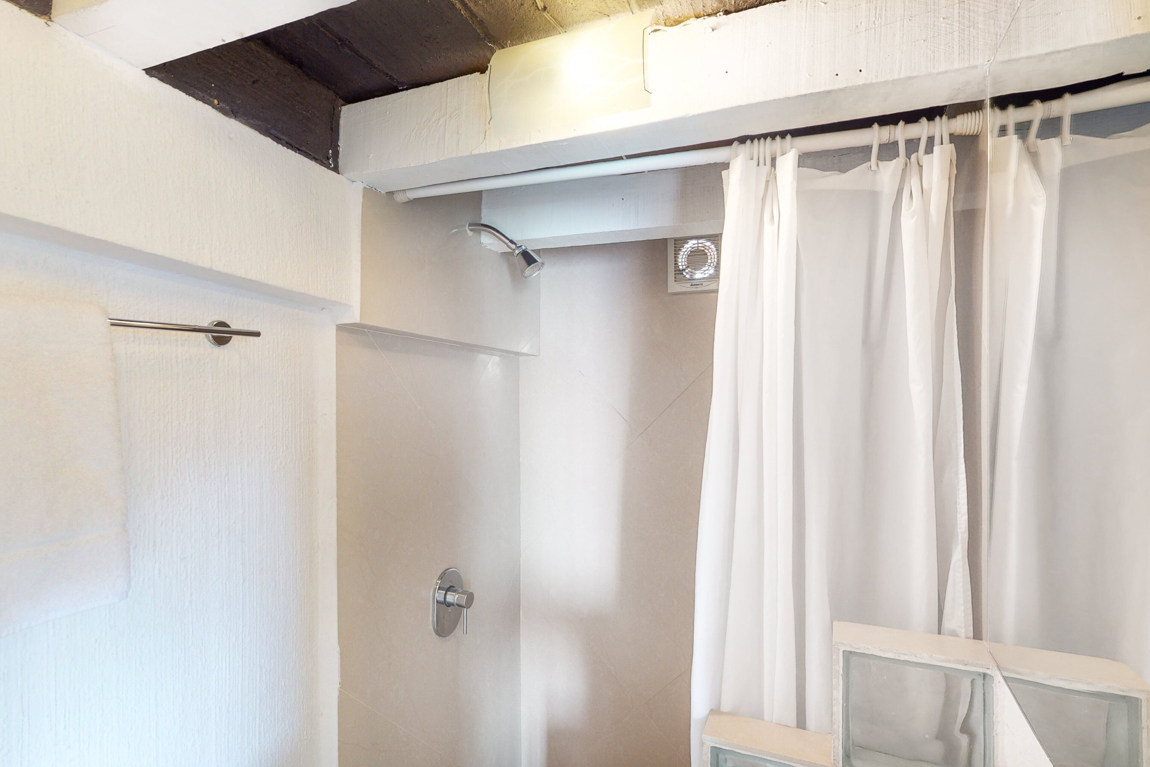 A bathroom with a shower, a door, and a curtain.
