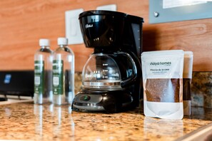 Máquina de café, garrafas de água e um saco de café em uma bancada de cozinha.