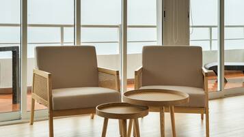 Dos sillones y una mesa redonda en una habitación con ventanas amplias.