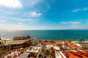 Um hotel à beira-mar com terraço no terraço, piscina e vista para o mar.