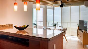 Una cocina moderna con una isla central, un bol de fruta y un comedor con vistas.
