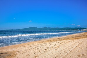A beach with a clear view of the ocean and distant mountains. - Stylish Condo With Covered Balcony, Pool & Pool Tables (Nuevo Nayarit)
