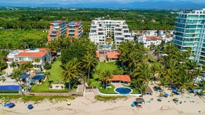 A resort with multiple buildings, a pool, and a beach area with umbrellas. - Stylish Condo With Covered Balcony, Pool & Pool Tables (Nuevo Nayarit)