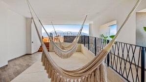 A hammock in a spacious, modern hotel corridor with a view of mountains and a balcony. - Resort Condo With Balcony, Scenic View, Rooftop Pool, & Well-equipped Kitchen (Puerto Vallarta)