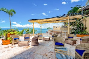 A covered outdoor seating area with wicker furniture and a view of the ocean. - Luxe 2nd-floor Condo With Endless Ocean Views, Pool, spa & Balcony (Puerto Vallarta)