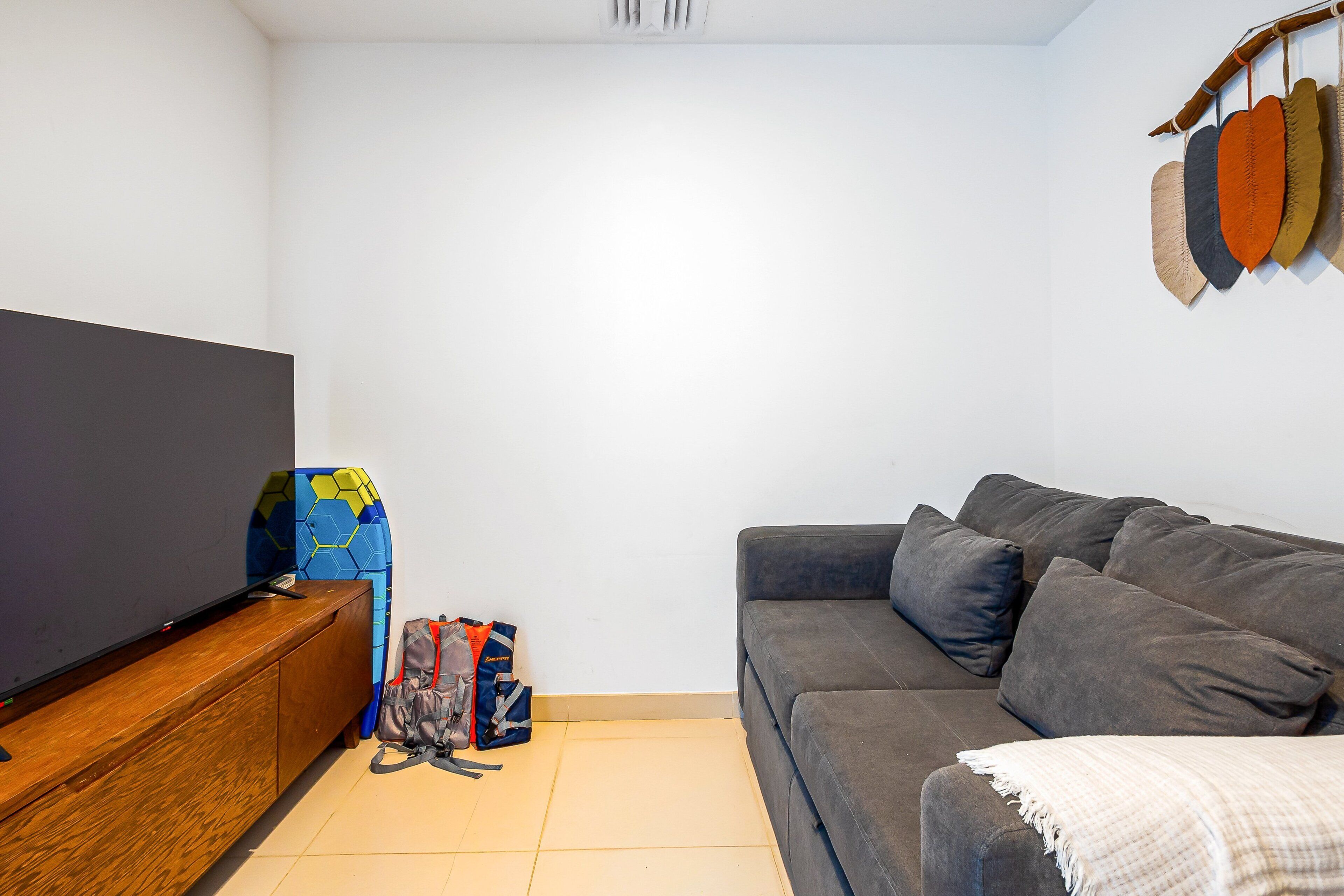A living room with a sofa, a TV, a wooden cabinet, and a backpack on the floor.