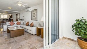A modern living room with a sofa, coffee table, and a potted plant. - Elegant Bayview Suite With Terrace Access, Full Kitchen, Pool, hot tub & gym (Puerto Vallarta)