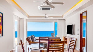 A dining area with a view of the sea, a ceiling fan, and a flat-screen TV. - Inviting Waterfront Condo With Amazing Pool, Balcony & W/D (Puerto Vallarta)