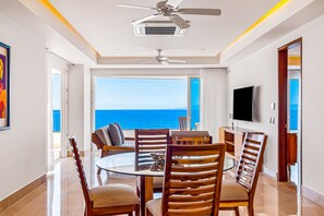 A dining area with a view of the sea, a ceiling fan, and a flat-screen TV. - Inviting Waterfront Condo With Amazing Pool, Balcony & W/D (Puerto Vallarta)