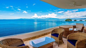 A balcony with wicker furniture, a glass table, and a view of the ocean. - Inviting Waterfront Condo With Amazing Pool, Balcony & W/D (Puerto Vallarta)