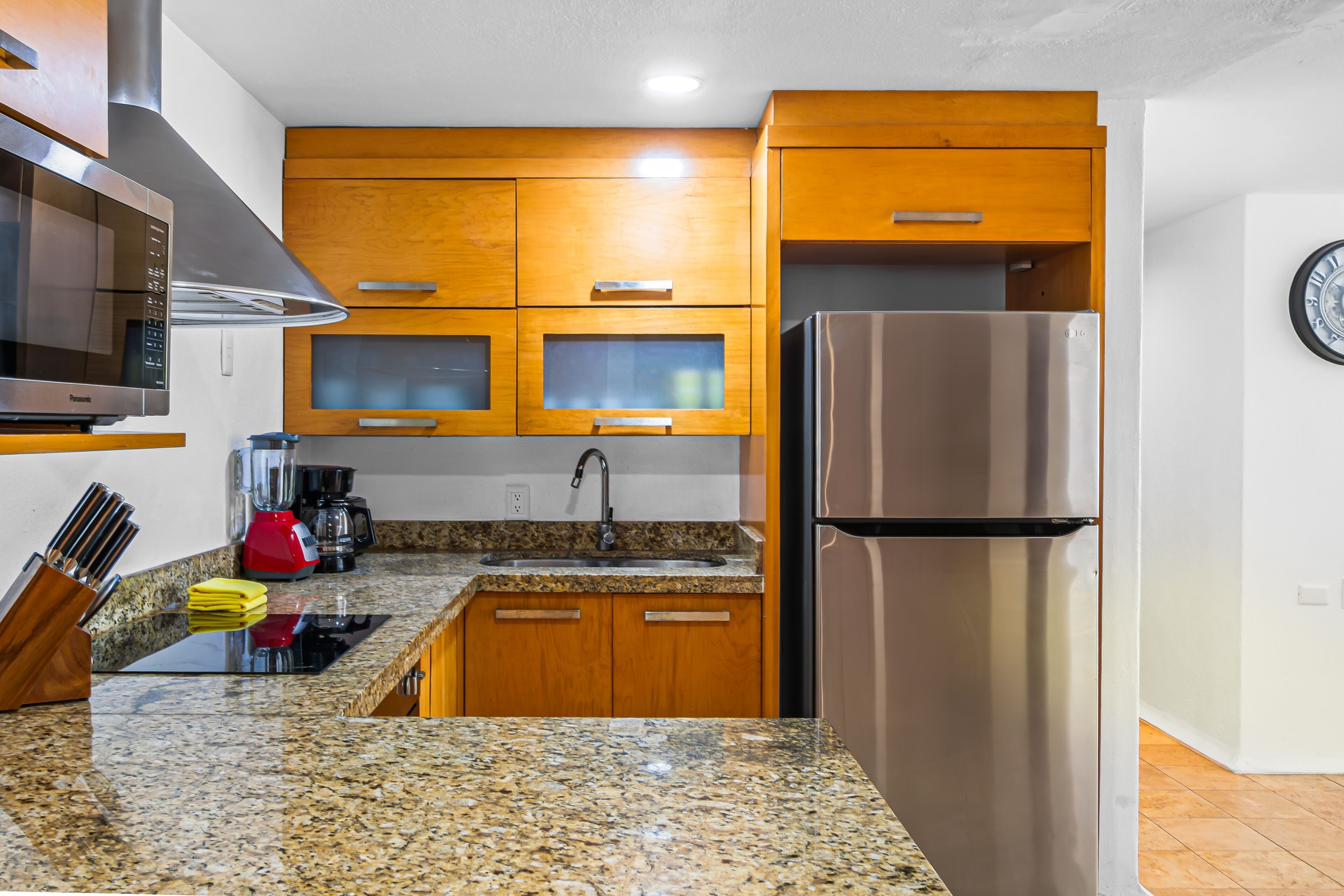 Eine moderne Küche mit Holzschränken, einem Edelstahlkühlschrank, einer Mikrowelle und einer Granitarbeitsplatte.