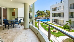A balcony with a dining area, a pool, and a well-maintained garden. - Stylish Beach Condo With Balcony View, Pool, Wifi & Central AC (Nuevo Nayarit)