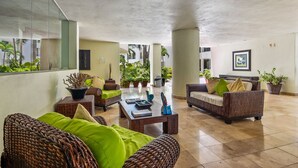 A spacious indoor area with wicker furniture, a coffee table, and potted plants. - Stylish Beach Condo With Balcony View, Pool, Wifi & Central AC (Nuevo Nayarit)