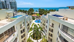 A high-rise hotel with multiple balconies, a swimming pool, and a view of the ocean. - Stylish Beach Condo With Balcony View, Pool, Wifi & Central AC (Nuevo Nayarit)