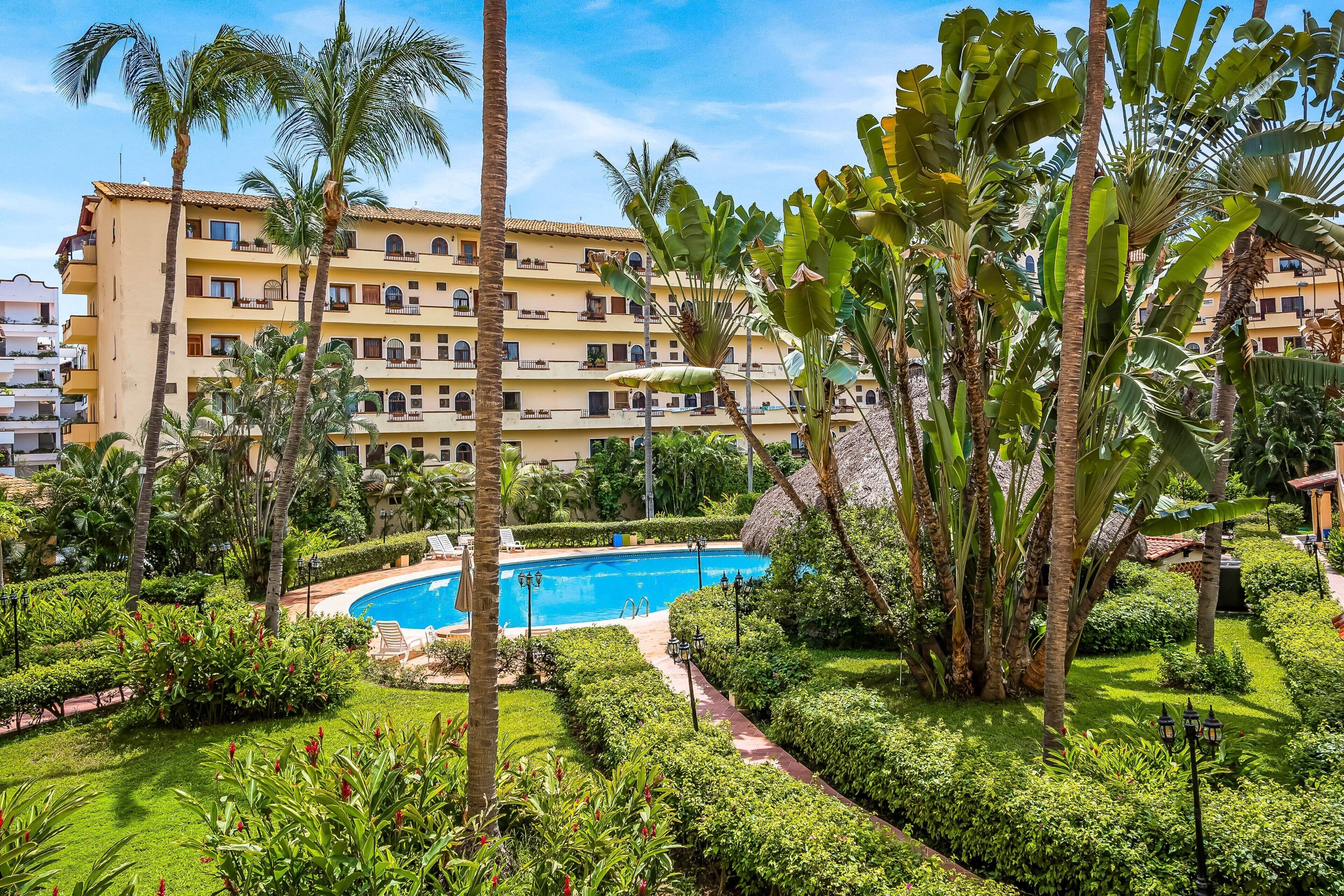 Un hotel con piscina rodeado de exuberante vegetación y palmeras.