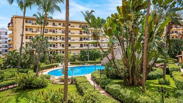 Ein Hotel mit Swimmingpool, umgeben von üppiger Vegetation und Palmen.