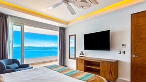 Ett hotellrum med en stor säng, en tv, ett träskåp och utsikt över havet.