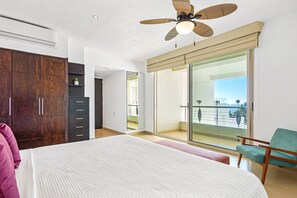 A bedroom with a bed, a wardrobe, a chair, a balcony with a view, and a ceiling fan. - Luxurious Retreat With a Scenic Terrace Pool & Modern Kitchen (Nuevo Nayarit)