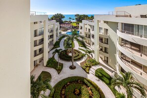 A modern hotel with a central courtyard, multiple balconies, and a view of the ocean. - Luxurious Retreat With a Scenic Terrace Pool & Modern Kitchen (Nuevo Nayarit)