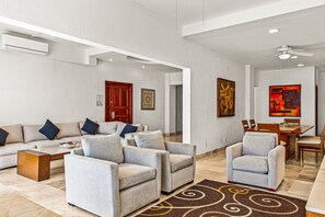 Un vaste espace de vie comprenant un canapé, des fauteuils, une table basse, une table à manger et des chaises.