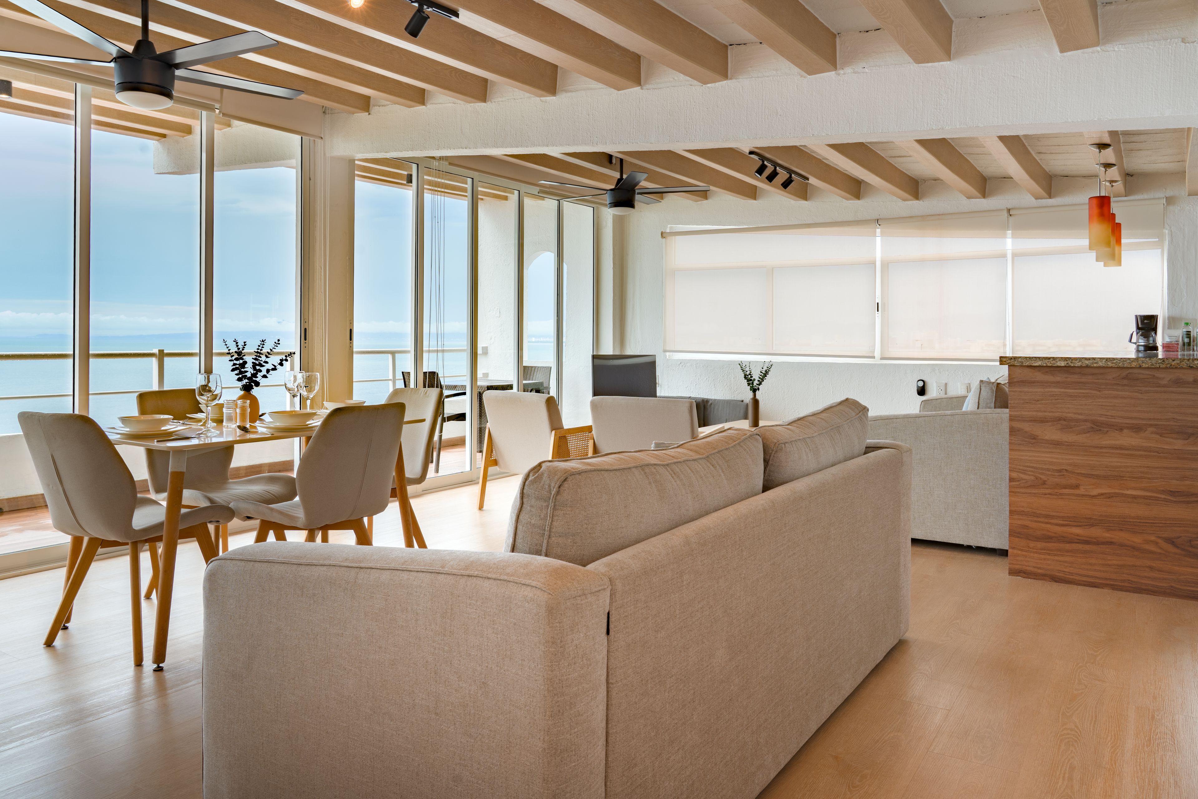 Ein modernes Wohnzimmer mit einer großen Couch, einem Essbereich und einer Küche.