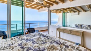 A bedroom with a large bed, a balcony with a view of the sea, and ceiling fans. - Stylish Coastal Condo With Pool, Private Balcony & Stunning Ocean Views (Puerto Vallarta)