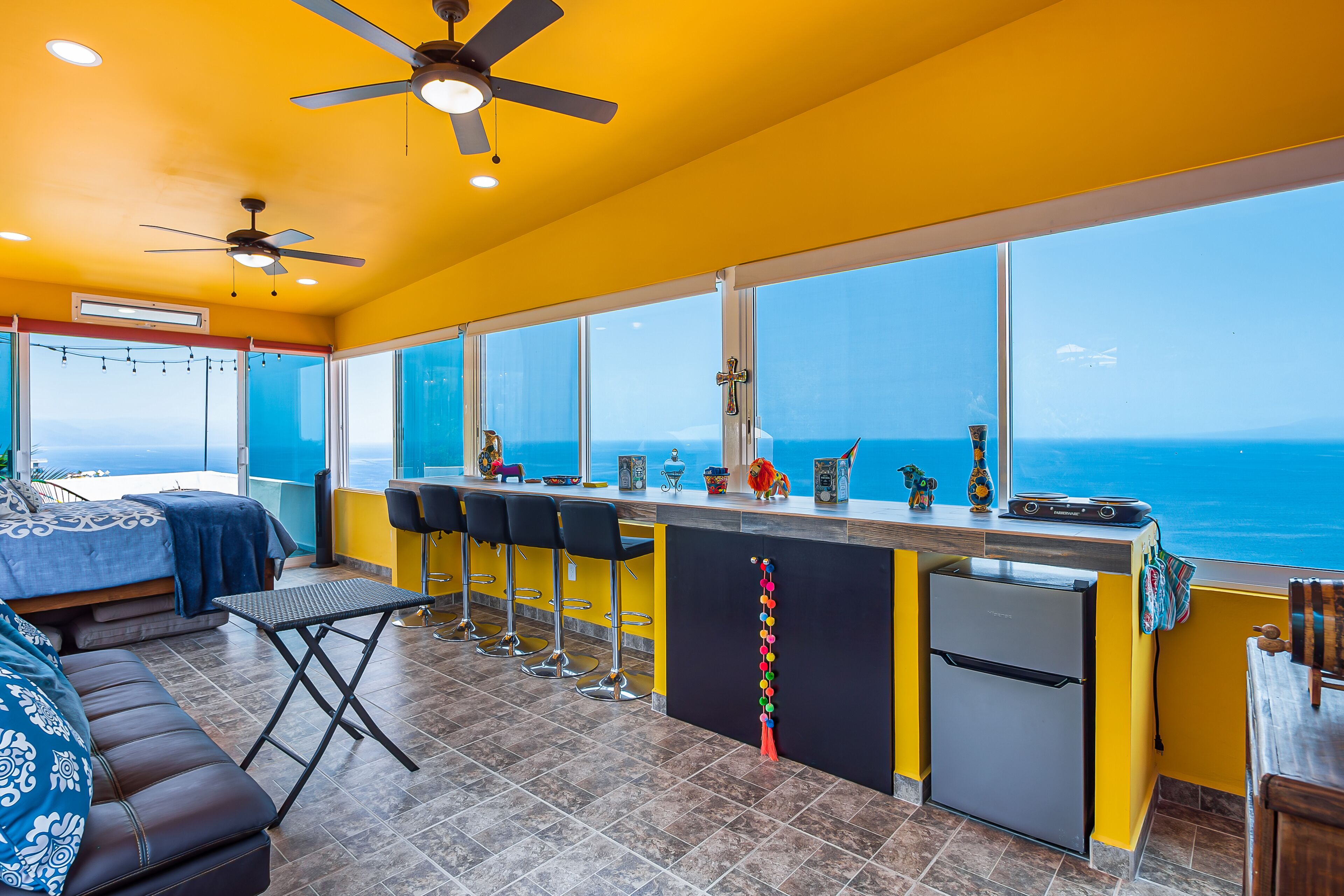 A kitchen with a view of the ocean, a bar area, and a seating area with a sofa and chairs.