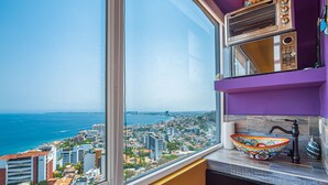 A bathroom with a large window, a colorful bowl sink, and a view of a coastal cityscape. - Gardenias Studio Studio in Puerto Vallarta With Panoramic Views (Puerto Vallarta)