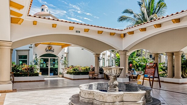 Ein Innenhof mit einem Brunnen, Palmen und einem Schild mit der Aufschrift Club House.