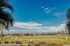 A golf course with a clear sky, palm trees, and distant mountains. - Golf Course-adjacent Getaway With Infinity Pool, Private Plunge Pool & Balcony (Nuevo Nayarit)