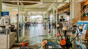 Eine Hotelhalle mit einer Rezeption, einer Sitzecke und Blick ins Freie.