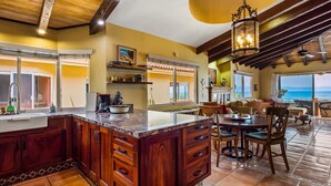 A spacious kitchen with a large island, wooden cabinets, and a view to the outside. - Oceanfront Condo With Pool, Balcony, Amazing Views, Washer/dryer, & Partial AC (Punta de Mita)