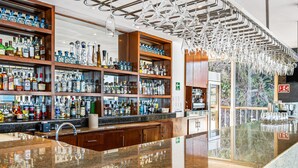 A bar area with shelves of liquor bottles, a granite countertop, and hanging light fixtures. - Upscale Coastal Suite With Private Terrace, Ocean Views, Pool & hot tub (Puerto Vallarta)