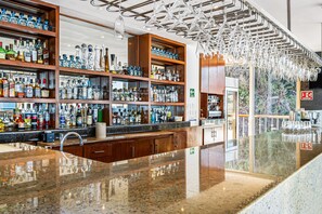 A bar area with shelves of liquor bottles, a granite countertop, and hanging light fixtures. - Upscale Coastal Suite With Private Terrace, Ocean Views, Pool & hot tub (Puerto Vallarta)