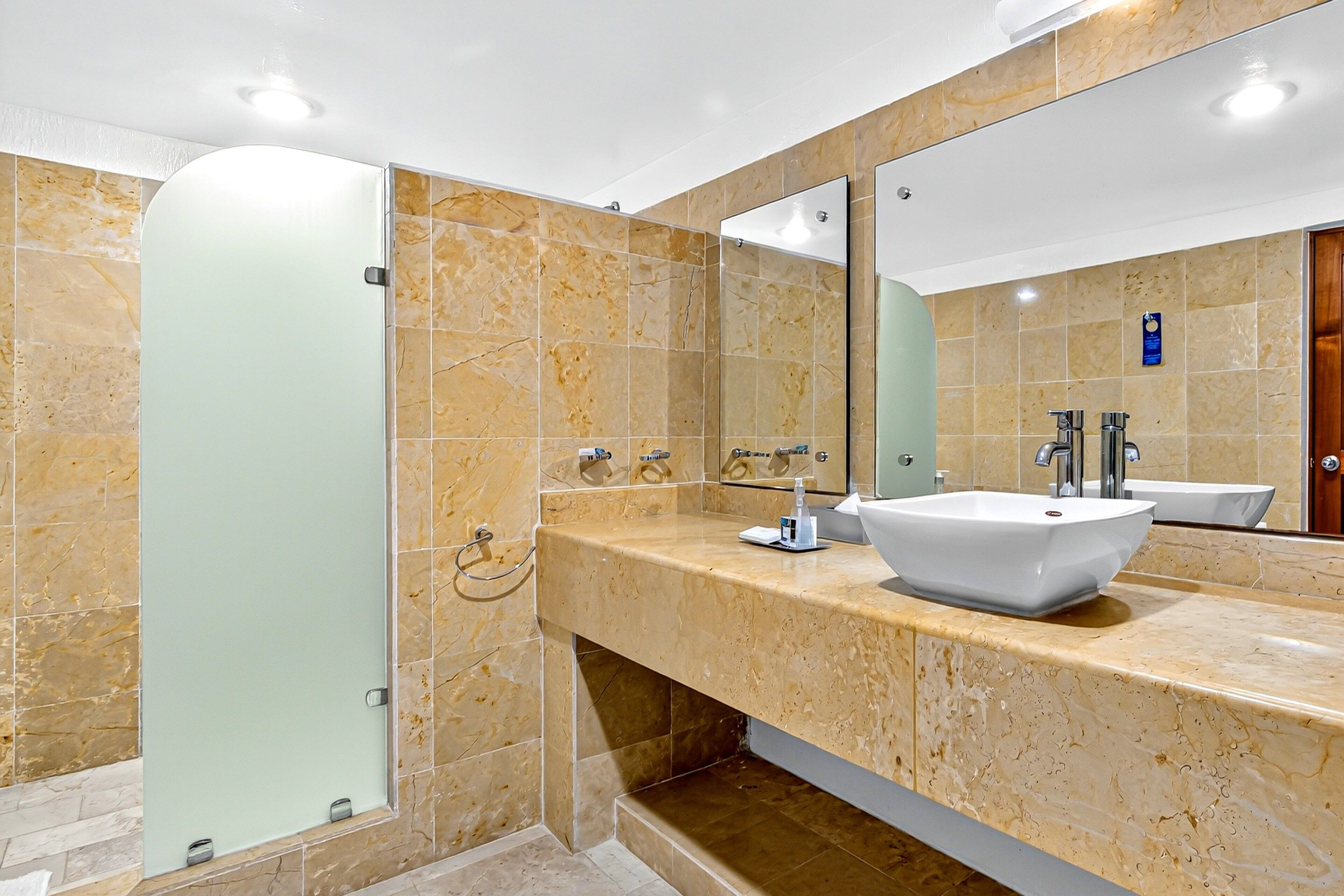 A modern bathroom with a glass shower enclosure, a white sink, and a large mirror.