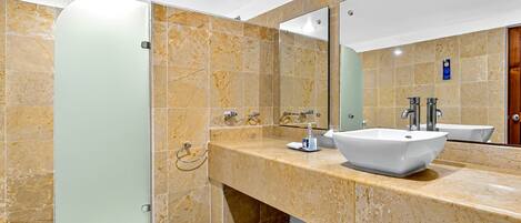 A modern bathroom with a glass shower enclosure, a white sink, and a large mirror.