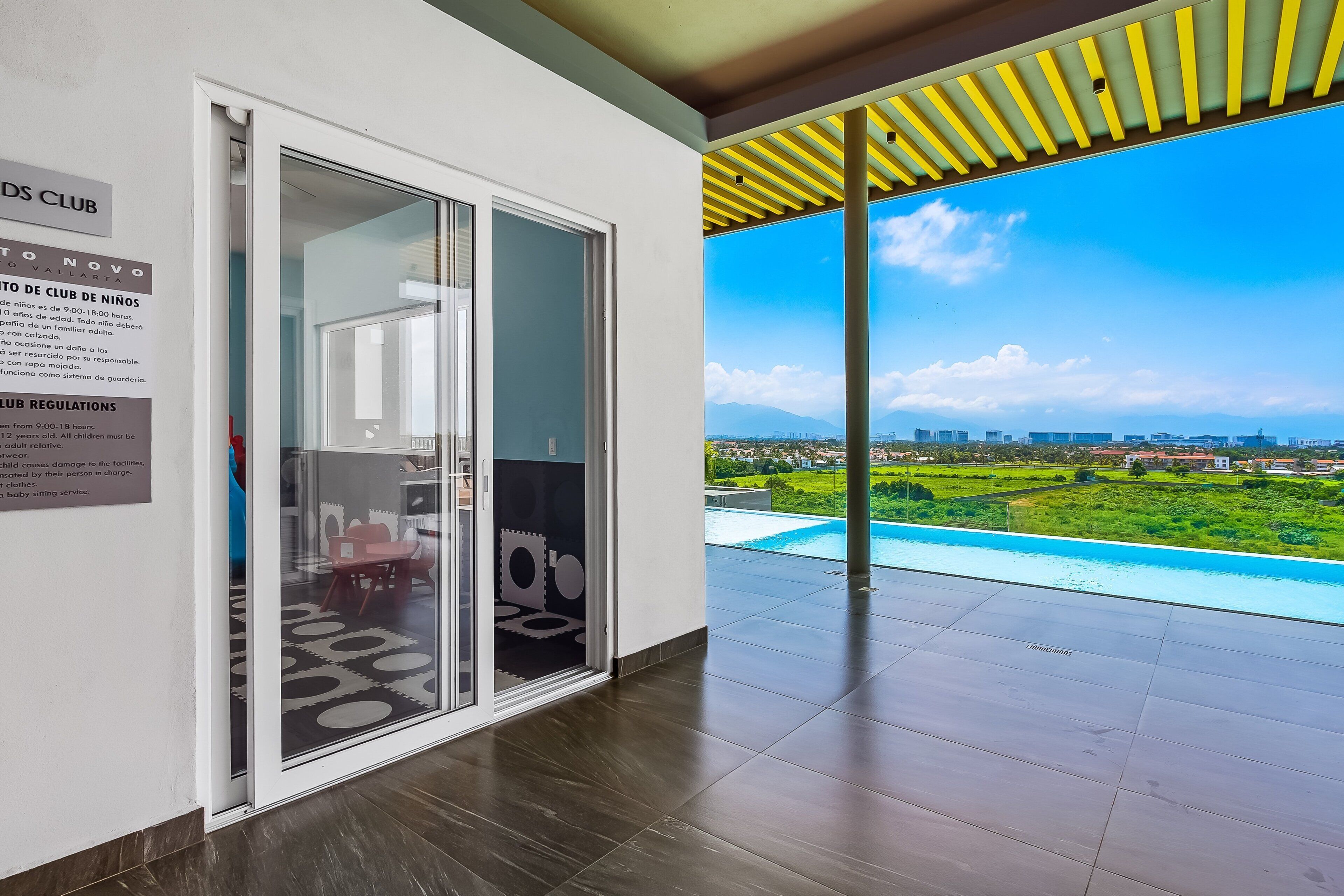 Un edificio moderno con puerta de vidrio que da a un balcón con vista a la piscina.