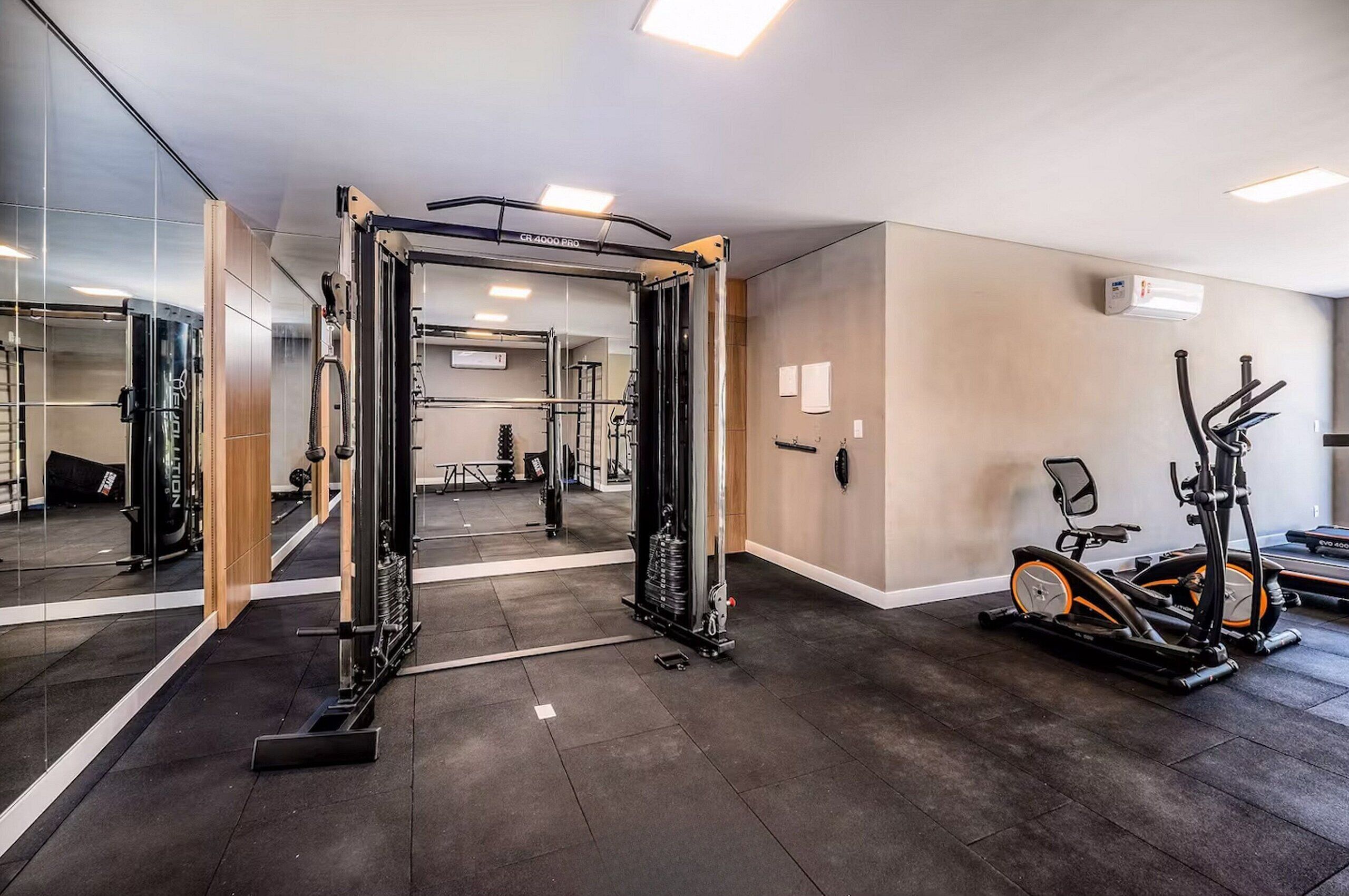 A gym with exercise equipment, a mirrored wall, and a treadmill.