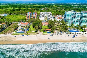 An aerial view of a coastal hotel with multiple buildings, a beach, and a view of the ocean. - Spacious Condo With Near the Beach With Resort-style Pool, Inviting Balcony (Nuevo Nayarit)