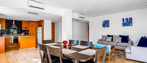 A modern living room with a dining area, a kitchen, and a sofa set.