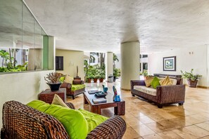 A spacious lobby with wicker furniture, a coffee table, and potted plants. - Spacious Condo With Near the Beach With Resort-style Pool, Inviting Balcony (Nuevo Nayarit)