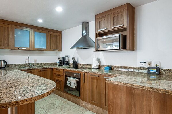 A kitchen with wooden cabinets, a stainless steel range hood, granite countertops, and a built-in oven. - Nitta Condo # 103 Stylish Condo Near the Beach With Ocean Views, On-site Pool (Nuevo Nayarit)